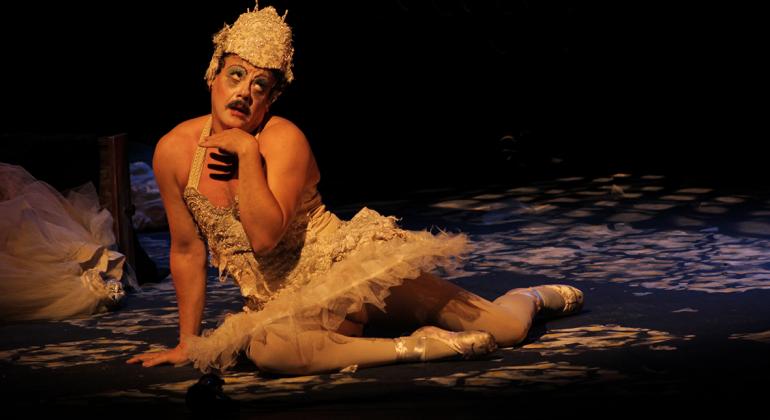 Amauri Reis celebra 35 anos de carreira com espetáculo no Teatro Marília Homem vestido de bailarina sentando no palco olhando para o alto.