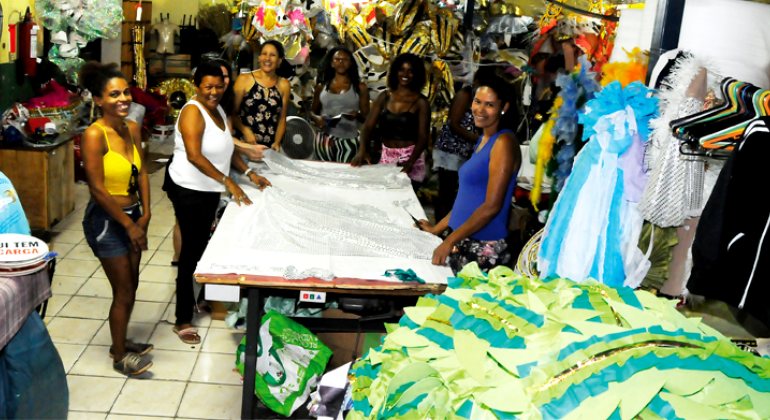 Acadêmicos de Venda Nova, escola de samba pentacampeã, entrará na avenida com 100 componentes a mais. Foto:Adão de Souza/PBH Sete mulheres organizando fantasias da escola de samba Acadêmicos de Venda Nova
