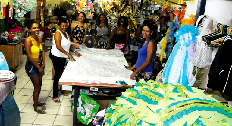 Sete mulheres organizando fantasias da escola de samba Acadêmicos de Venda Nova