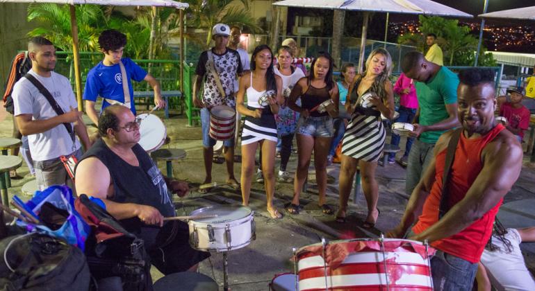 Cerca de 11 membros do bloco caricato Mulatos do Samba tocam diversos instrumentos musicais.