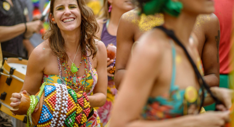 Foliões em trajes coloridos pulando carnaval.