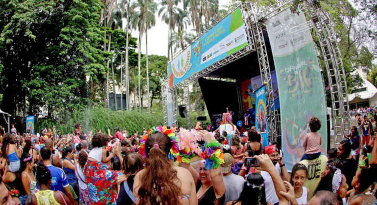 Crianças brincam o carnaval em frente a um palco montado no Parque Municipal