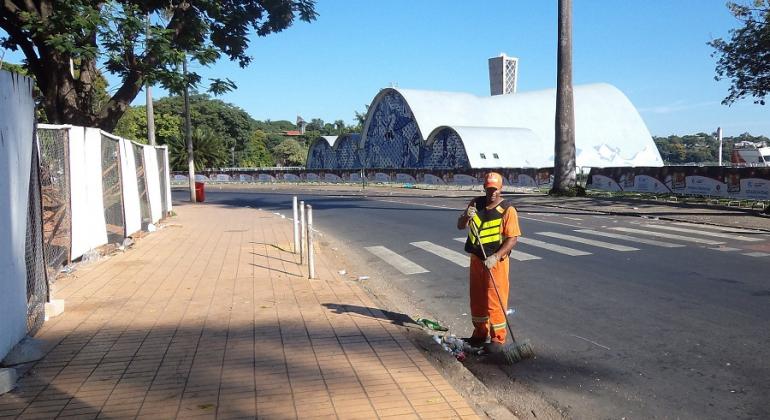 Gari limpa rua ao lado da Igreja São Francisco de Assis, a Igrejinha da Pampulha.