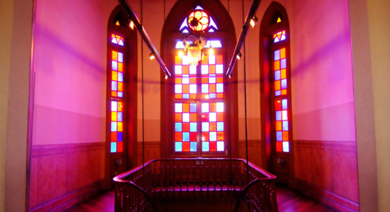 Foto: Adão de Souza/PBH Interior do Museu da Moda, com vitrais nas cores azul e vermelho em sala com escada.
