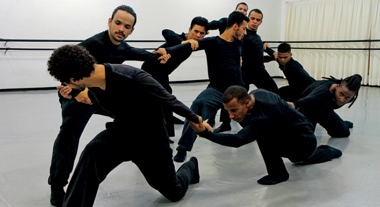 Foto: Divulgação/PBH Oito homens vestidos de preto interagem em apresentação de dança.