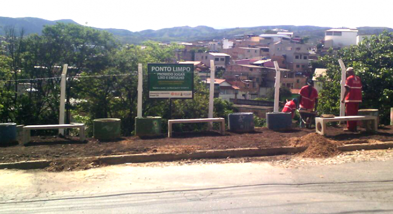 Terreno na Vila Pinho é revitalizado com projeto paisagístico. Três funcionários da slu realizando a limpeza de terreno na Vila Pinho