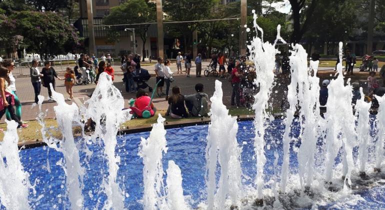 Dia 18 de fevereiro, primeiro domingo após o Carnaval, é a data da retomada das atividades do “BH é da Gente – Savassi”. Foto: Vilma Tomaz/PBH Fonte de água da Savassi à frente; ao fundo, pessoas passeiam ou descansam, sentadas.