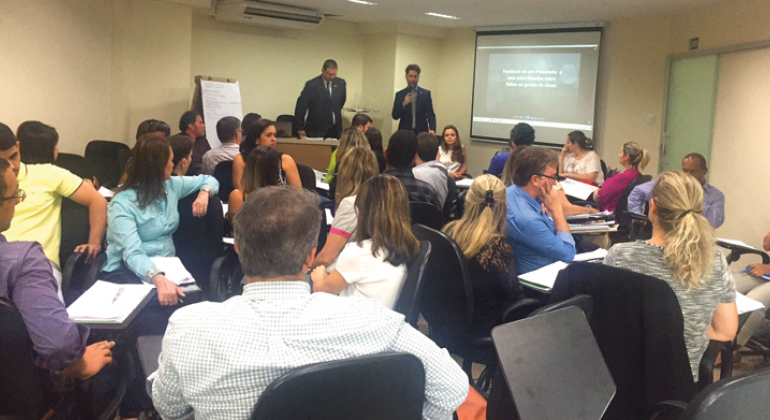 Iniciativa visa capacitação dos servidores da Controladoria-Geral do Município e das empresas estatais de Belo Horizonte. Foto: Divulgação PBH Dois homens, de pé, dando capacitação para cerca de 20 pessoas sentadas.