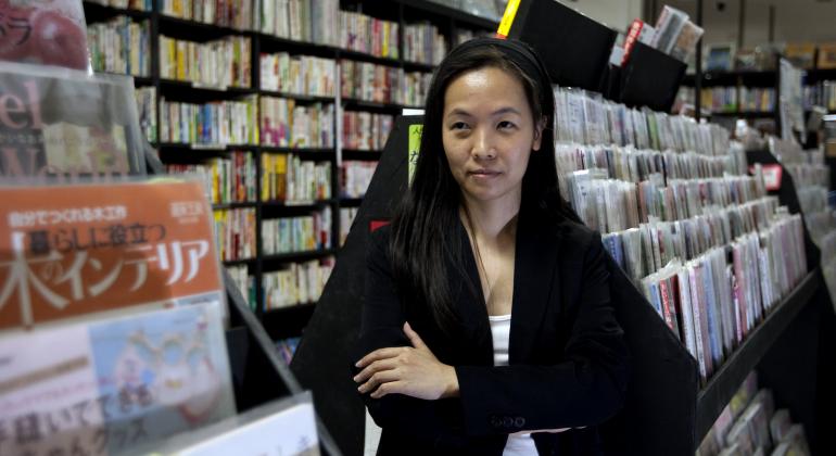 Lenda do mangá nacional, Érica trabalhou em séries de destaque como “Street Fighter Zero 3”, “Holy Avenger” e “GGW". Foto: Divulgação Quadrinista Érica Awano em frente a uma estante repleta de quadrinhos