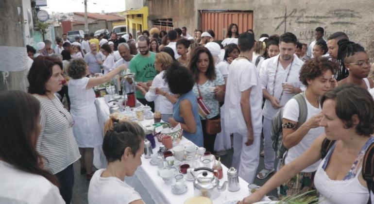 Mais de trinta pessoas de branco em torno de uma mesa da comunidade quilombola Manzo. 