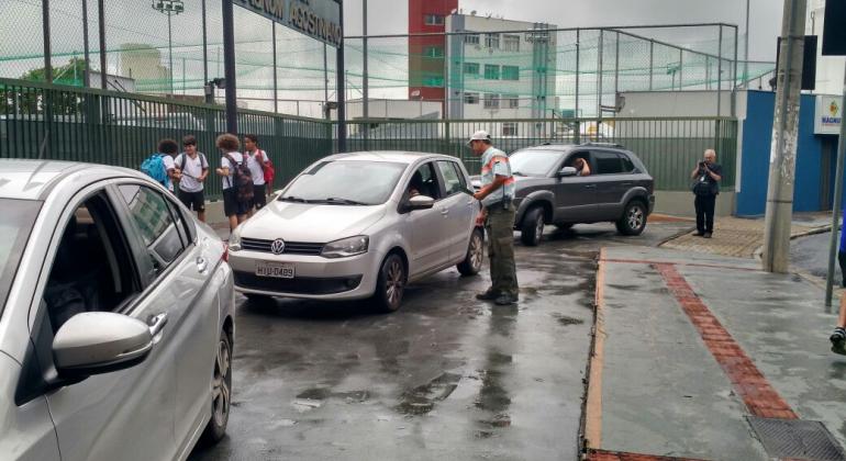 Operação Volta às Aulas começa na quinta-feira, dia 1º/2 Operação volta às aulas. Três carros na imagem. Agente da BHTrans orienta um deles em frente a uma escola.