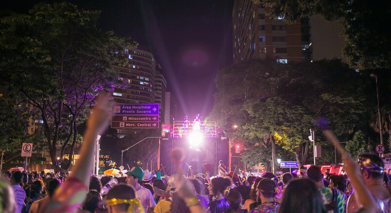 PBH realiza operação especial para desfile na quarta, dia 7/2. Foto: Divulgação/PBH Foliões com as mãos para cima desfilam na Avenida Afonso Pena à noite.