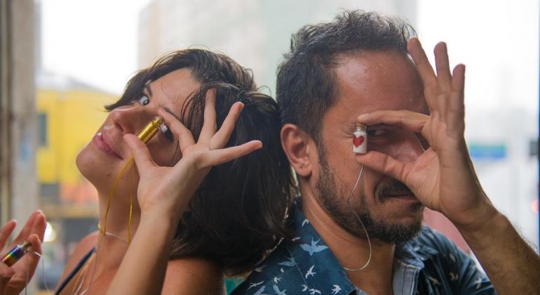 Um grupo cada vez maior de empreendedores tem usado a criatividade para buscar uma forma de garantir uma renda extra no Carnaval 2018. Foto: Divulgação/PBH Muler e homem mostram glitter no vidrinho, produto que tem sido comercializado com sucesso no Carnaval de BH.