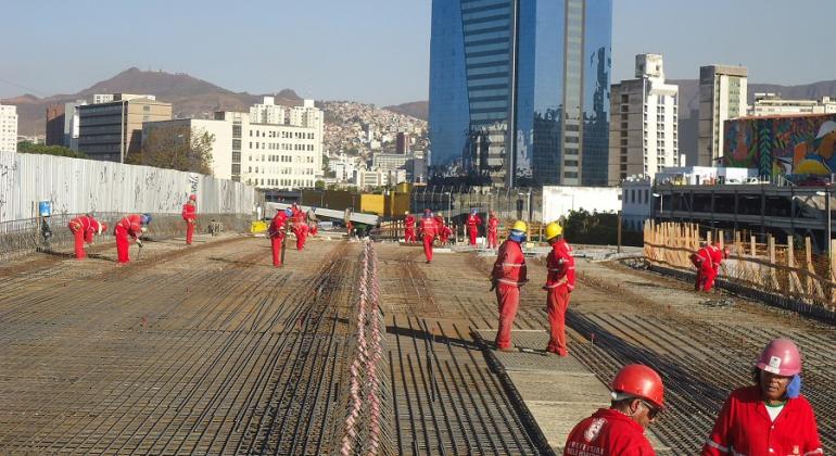 Cerca de 14 funcionários trabalham na construção do Viaduto Leste, na Lagoinha, ao fundo, prédios e cidade.