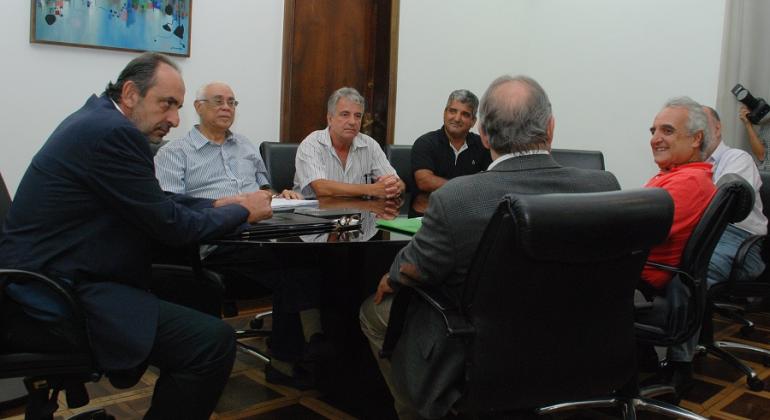 O prefeito Alexandre Kalil apresentou para representantes Maternidade Sofia Feldman a proposta de assumir a direção do hospital. Foto: Stênio Lima/PBH O prefeito de Belo Horizonte, Alexandre Kalil, os secretários municipais de Saúde, Jackson Machado, e de Fazenda, Fuad Noman, e representantes da Maternidade Sofia Feldman, sentados em uma mesa oval, conversando.