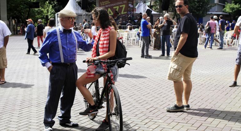 Confira as atividades gratuitas que acontecem em BH neste fim de semana. Foto: Amira Hissa/PBH Senhor de suspensórios e boina conversa com jovem de bicicleta no cruzamento das avenidas Cristóvão Colombo e Getúlio Vargas. Pessoas transitam ao redor.