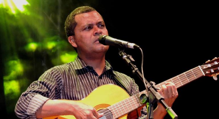 No palco, o músico Walter Dias se apresenta tocando violão.