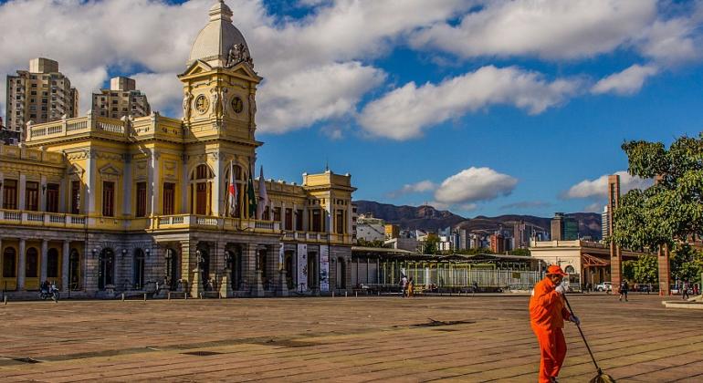 Praça da Estação é varrida três vezes ao dia durante a semana, tem plantões de varrição aos domingos e feriados e reforço em dia de evento. Foto: Marcelo Santos Gari varre Praça da Estação, ao fundo, prédio do Museu de Artes e Ofícios.