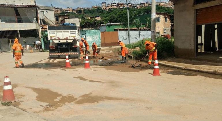 Ações emergenciais e de prevenção no período de chuvas são realizadas pela Prefeitura Municipal de Belo Horizonte. Foto: Divulgação PBH Garis da SLU recolhem lama de uma esquina próximo a um caminhão.