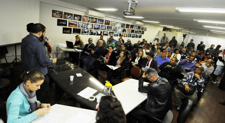 Mais de 30 camelôs, sentados em sala, aguardam comunicado de técnicos da Prefeitura. Foto ilustrativa. 