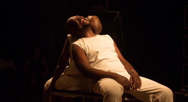 O espetáculo “O Negro Conta”, inspirado nas memórias de dois artistas negros, está em cartaz no Chico Nunes de 13 a 24 de abril. Foto: Maria Rita Fonseca Dois homens negros de calça e camiseta branca sentados, um de costas para o outro, com as cabeças lado a lado.
