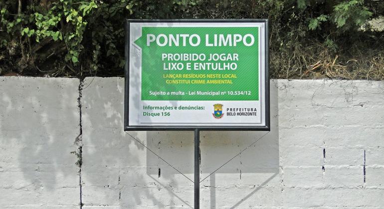 Na quinta-feira, dia 26 de abril, a Prefeitura irá implantar mais um Ponto Limpo rua Guido Leão, na região de Venda Nova. Foto: Divulgação PBH À frente de muro pintado de branco, placa com os dizeres: Ponto Limpo: proibido ogar lixo e entulho.