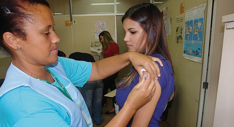 Técnica de saúde vacina braço de mulher contra a Influenza.