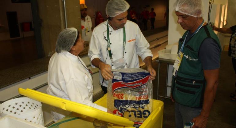 Vigilância Sanitária da Prefeitura atua para garantir consumo de produtos seguros e de qualidade no estádio do Mineirão. Foto: Karen Moreira/PBH Fiscal da Vigilância sanitária verifica as condições de armazenamento dogelo com dois funcionários do setor de venda de alimentos e bebidas do Mineirão.