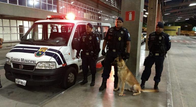 Operações da Guarda Municipal já apresentam balanços parciais referentes a 2018. Foto: Divulgação/PBH Veículo da Gurda Municipal em Estação do Move. Ao lado, três agentes e um cachorro.