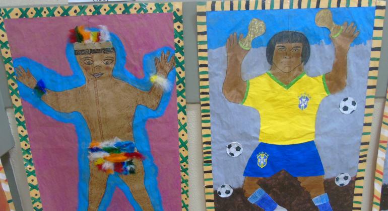 Dois painéis em exposição. Um deles mostra o índio vestido somente com penas, e os dizeres "Lugar de índio é onde ele quiser; O outro mostra o índio com o uniforme da Confederação Brasileira de Futebol e os dizeres "Lugar de índio é no esporte".