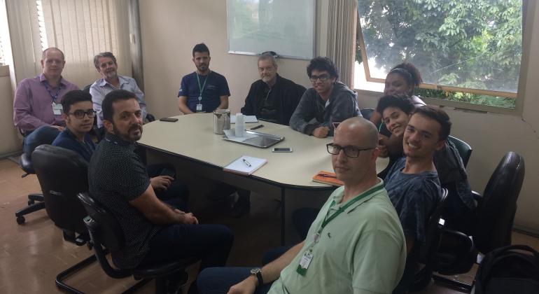 Onze pessoas sentadas em uma mesa de reunião. Entre elas, funcionários da Prodabel, alunos do Cotemig e representantes da BHTrans.