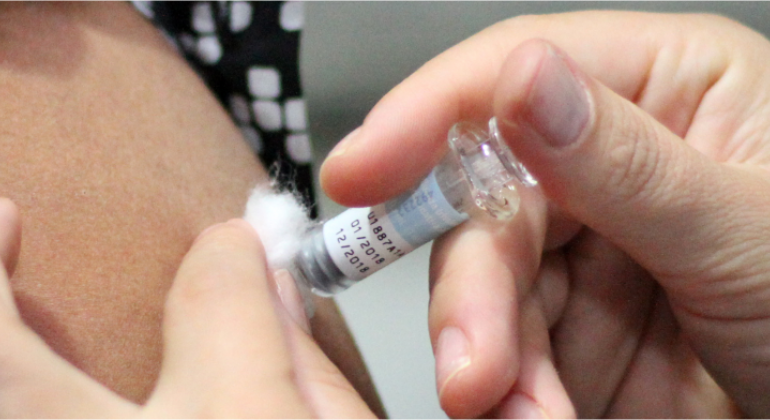Um profissional da saúde aplica vacina contra gripe em um servidor municipal. 