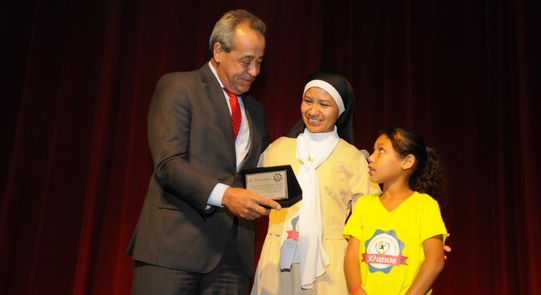 Procurador Geral do Município, Tomáz de Aquino Resende, recebe homenagem de criança e mulher no aniversário de 30 anos de instiuição parceira da PBH. 