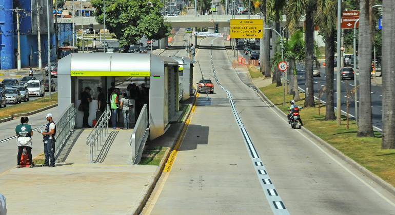 Estação Move Antônio Carlos, com pessoas entrendo e saindo; dois carros transitam na pista à direita. 