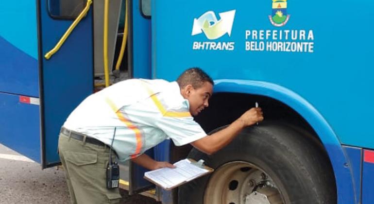 Fiscal da BHTrans ferifica detalhe sobre roda de ônibus. 