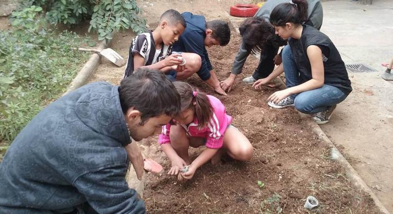 Monitores e jovens integrantes do Projeto Sombra e água fresca participam de oficina ao ar livre, cultivando plantas.