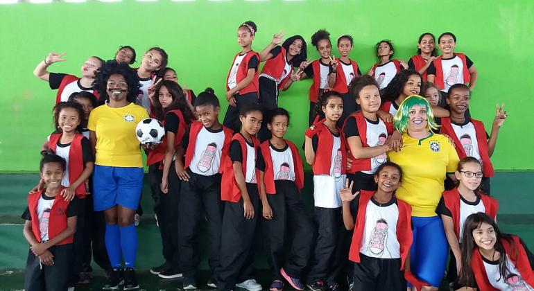 Alunos e professoras na arquibancada durante jogos do projeto Copa do Mundo. 