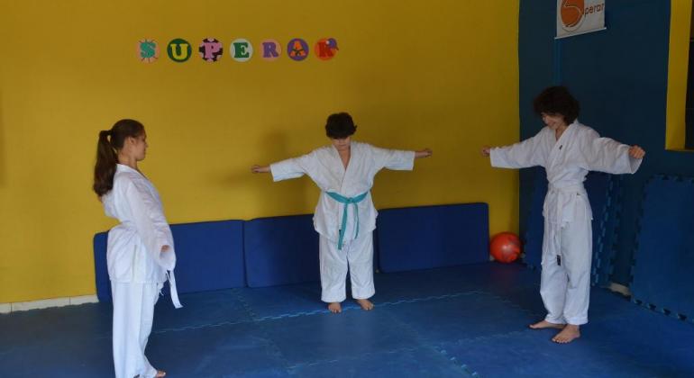 Três atletas do programa superar em um tatami e trajando kimono.