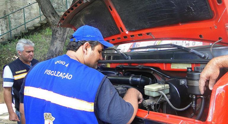 Técnico da Prefeitura confere motor de veículo. 