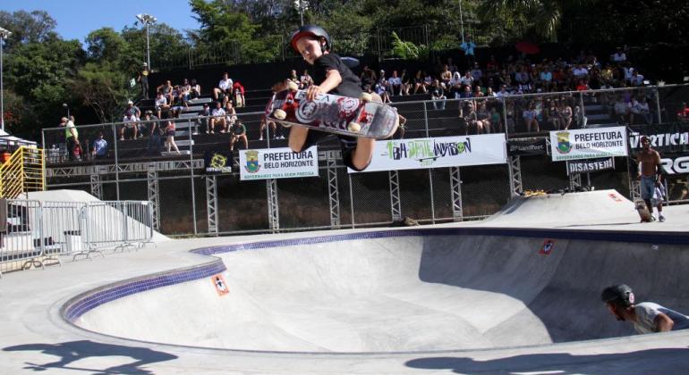 A havaiana Hunter Long e o californiano Eddie Elguera são atrações internacionais do 2º BH Skate Invasion, nos dias 23 e 24/6. Foto: Rodrigo Clemente/PBH Criança dá salta de skate no ar em pista no Parque Lagoa do Nado; ao fundo, plateia acompanha. Foto de edição do evento Skate Invasion em 2017.