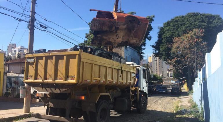 Carcaça de veículo sendo retirada por caminhão guindaste da PBH