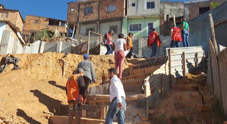 Moradores, voluntários e funcionários da PBH subindo escadas nas obras de área de risco da Vila Pedreiro Prado Lopes.
