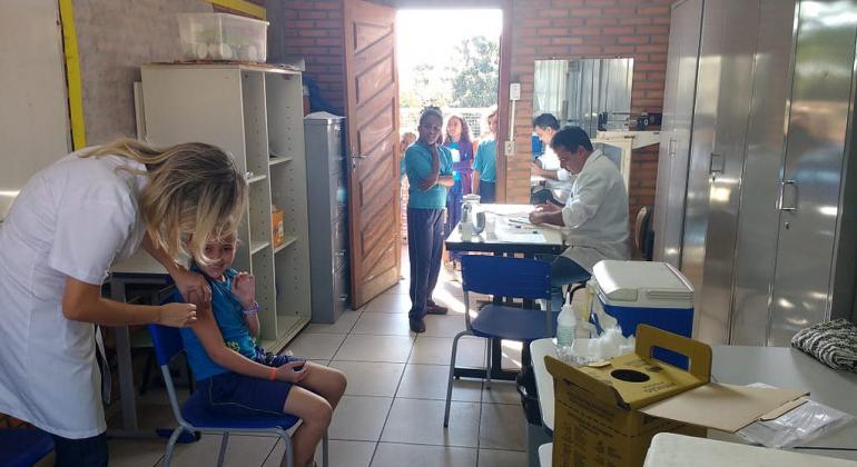 Estudantes de Venda Nova são imunizados contra HPV. Foto: Divulgação/PBH Dois profissionais da saúde vacinando crianças da Rede Municipal de Ensino