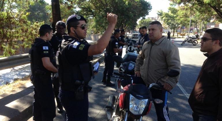 Quatro gaurdas municipais fazem blitz educativa de prevenção ao uso de cerol; um deles aborda motorista de moto.