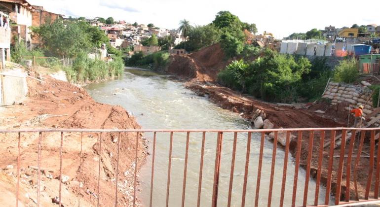 Prefeitura de Belo Horizonte reabre licitação para obras no Ribeirão do Onça Foto feita de cima de uma ponte que passa sobre o Ribeirão do Onça. Nas margens do Ribeirão, há casas e áreas em obra.