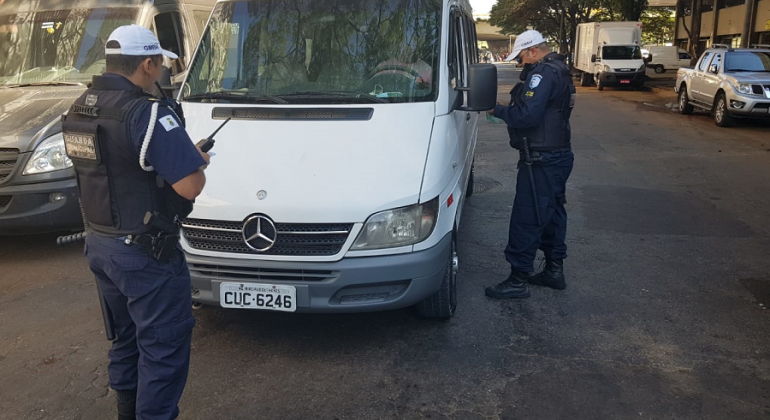 Operação da Guarda Municipal de combate ao transporte clandestino de passageiros já soma mais de 200 autuações. Foto: Divulgação PBH Dois Guardas municipais fiscalizam van branca.