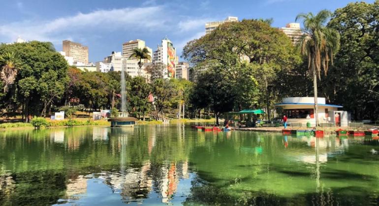 Confira os principais eventos gratuitos que acontecem em BH neste fim de semana, até o dia 8/7. Foto: Stênio Lima Lago da Parque municipal, com árvores e prédios ao fundo, durante o dia.