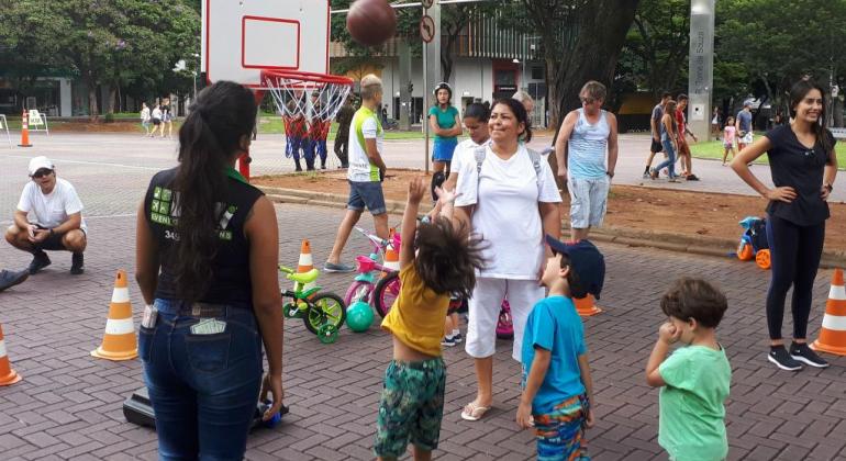 Foto: Vilma Tomaz/PBH Três crianças brincam de vôlei acompanhadas por duas mulheres.