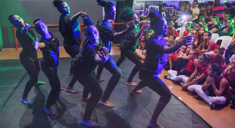 FMC abre inscrições para a Escola Livre de Artes – Projeto Arena da Cultura bailarinas dançam em palco e crianças assistem