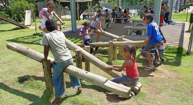 Programa Escola nas Férias vai promover revitalização de praça em Venda Nova Crianças brincam em gangorra em Parque da cidade